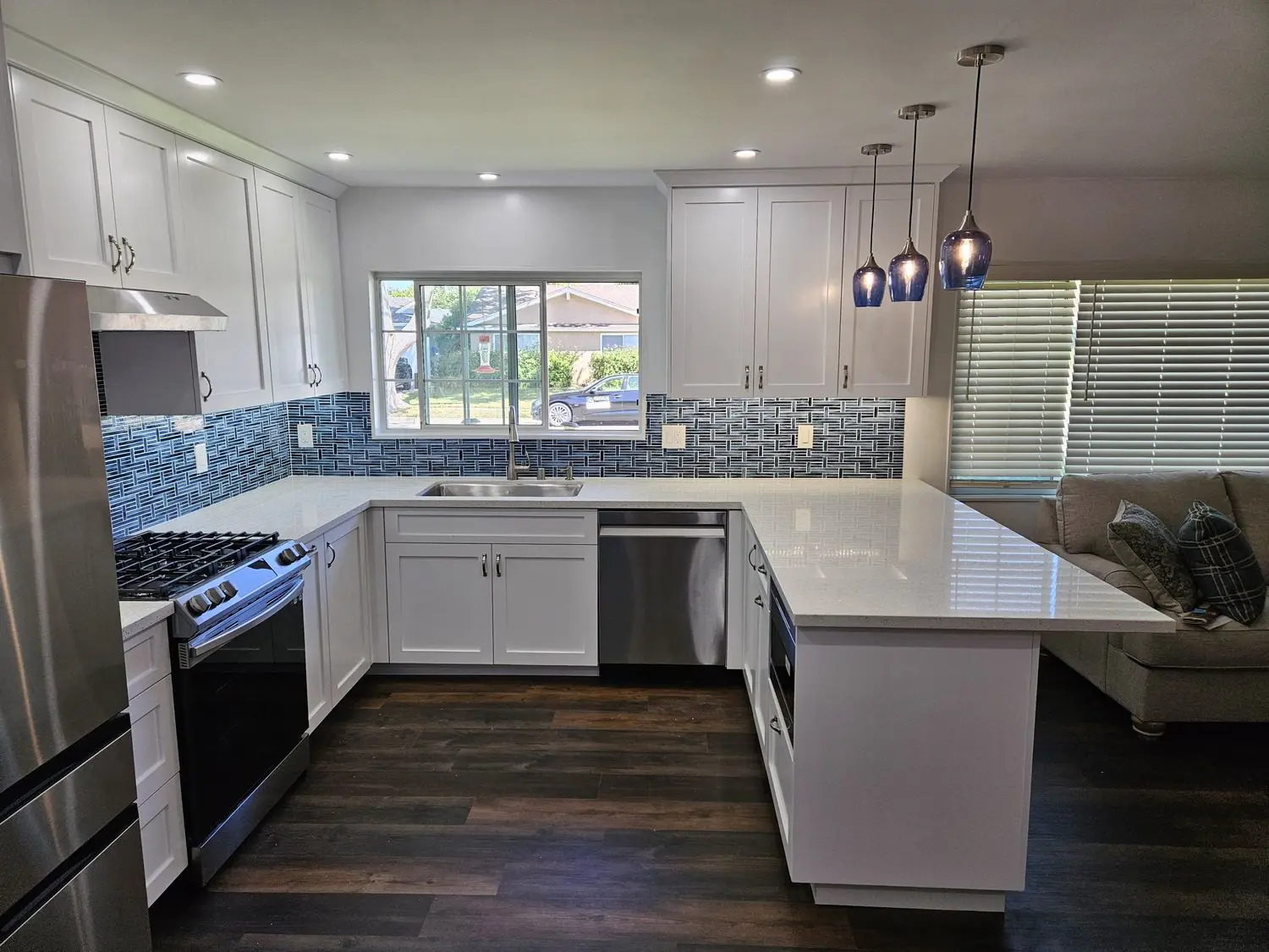 A kitchen with white cabinets and wood floors.