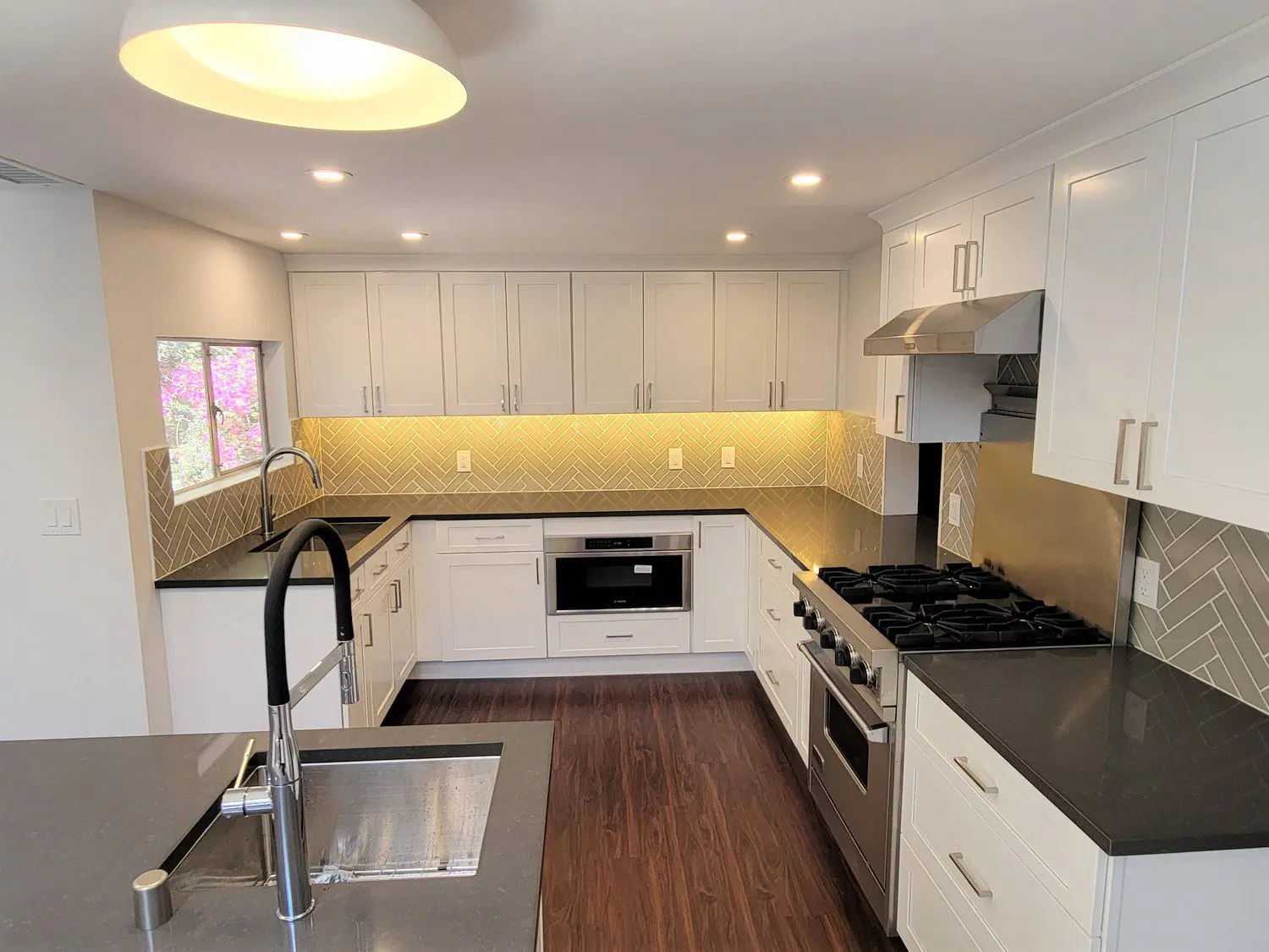 A kitchen with white cabinets and black counter tops.