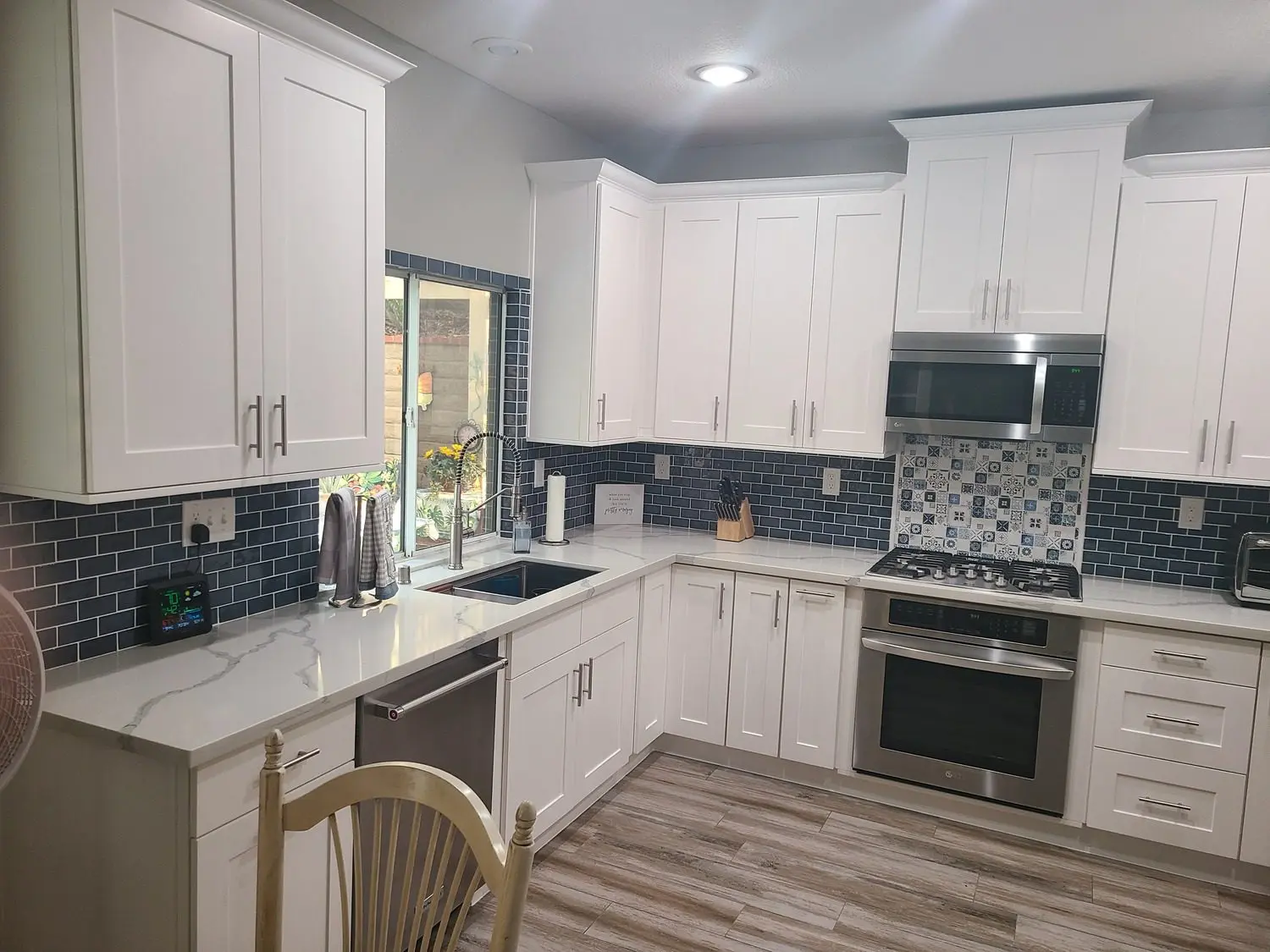 A kitchen with white cabinets and wood floors.