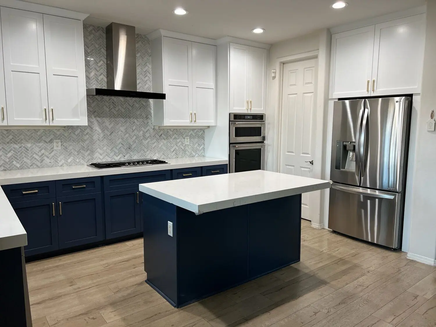 A kitchen with white cabinets and blue island.