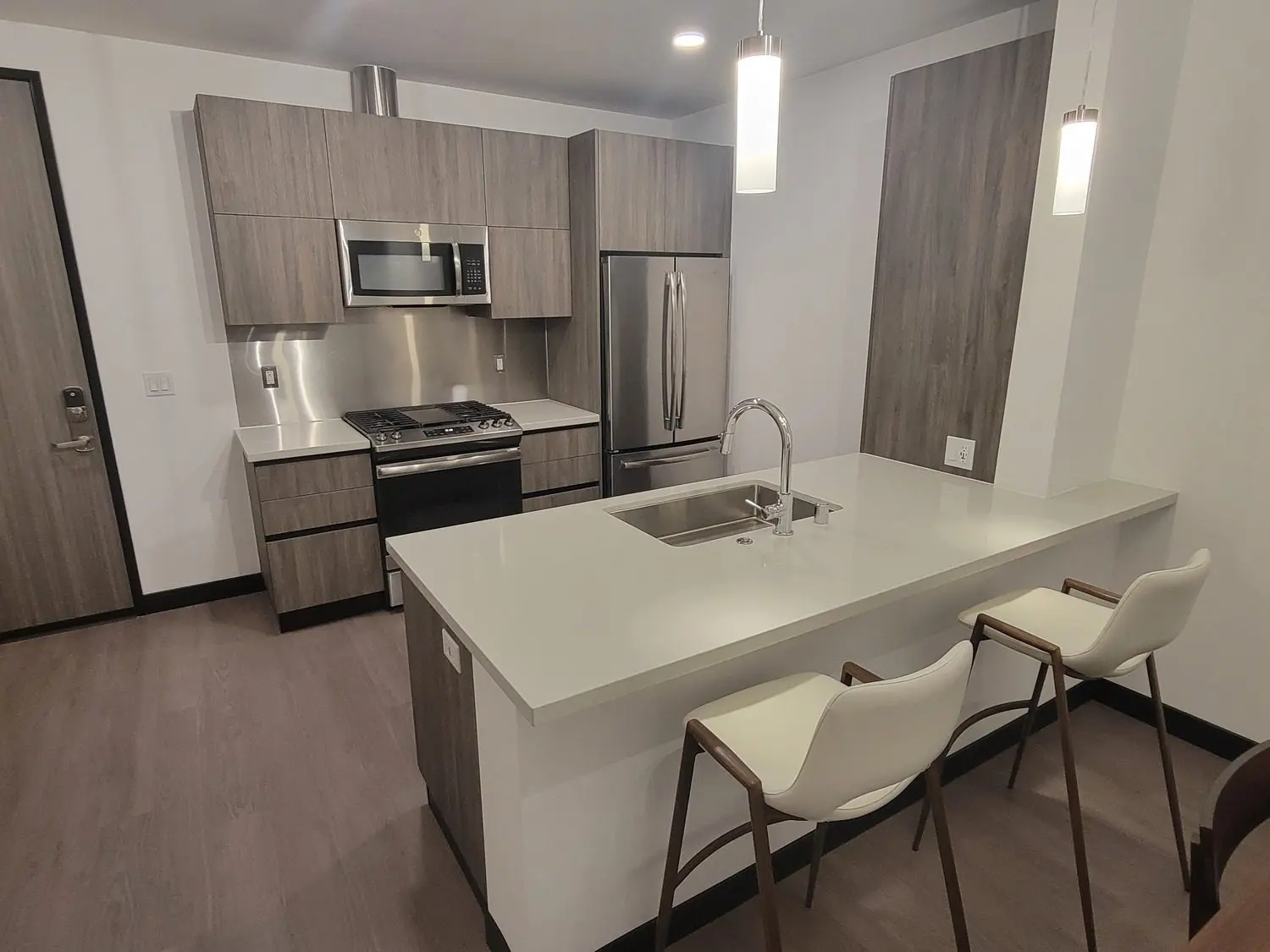 A kitchen with a sink, stove and refrigerator.