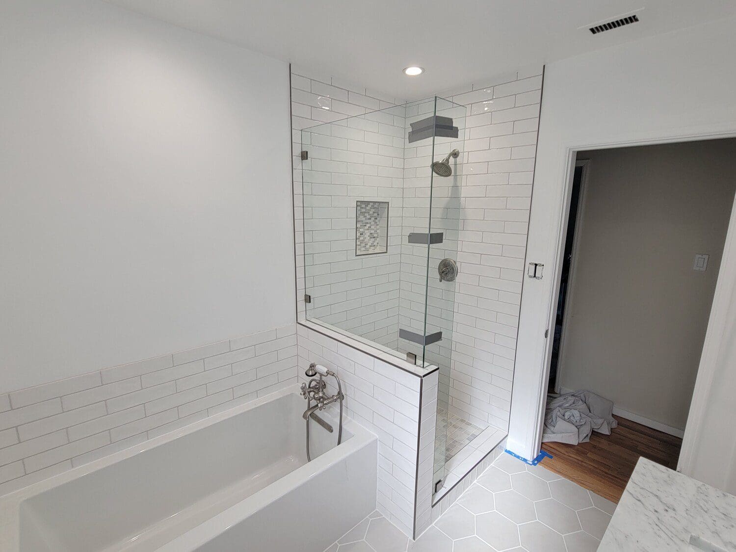 A bathroom with white tile and a tub