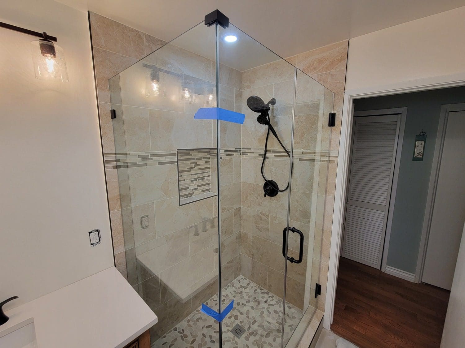 A bathroom with a glass shower door and tile floor.