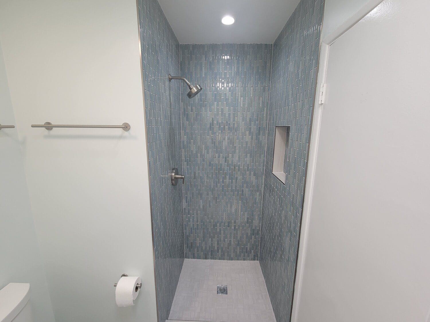 A bathroom with a walk in shower and tiled walls.