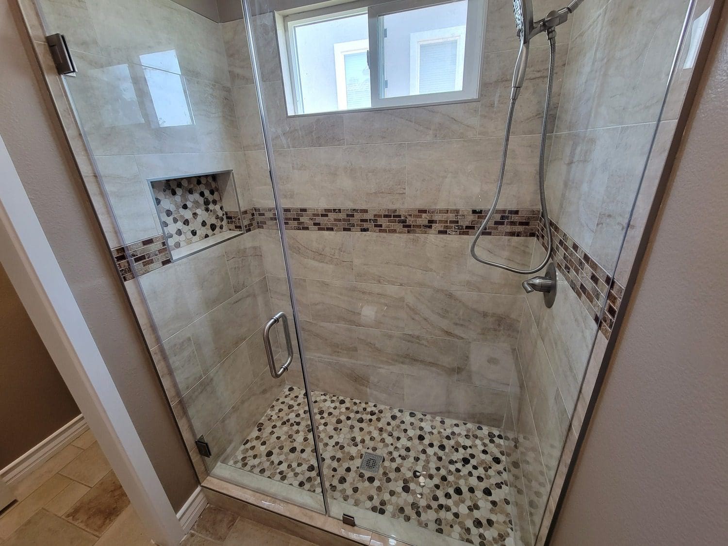 A shower with a glass door and tiled floor