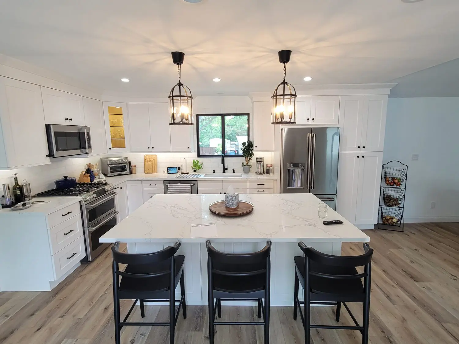 A kitchen with white cabinets and black chairs