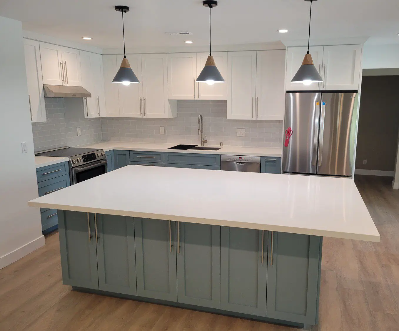 A kitchen with white cabinets and blue island.