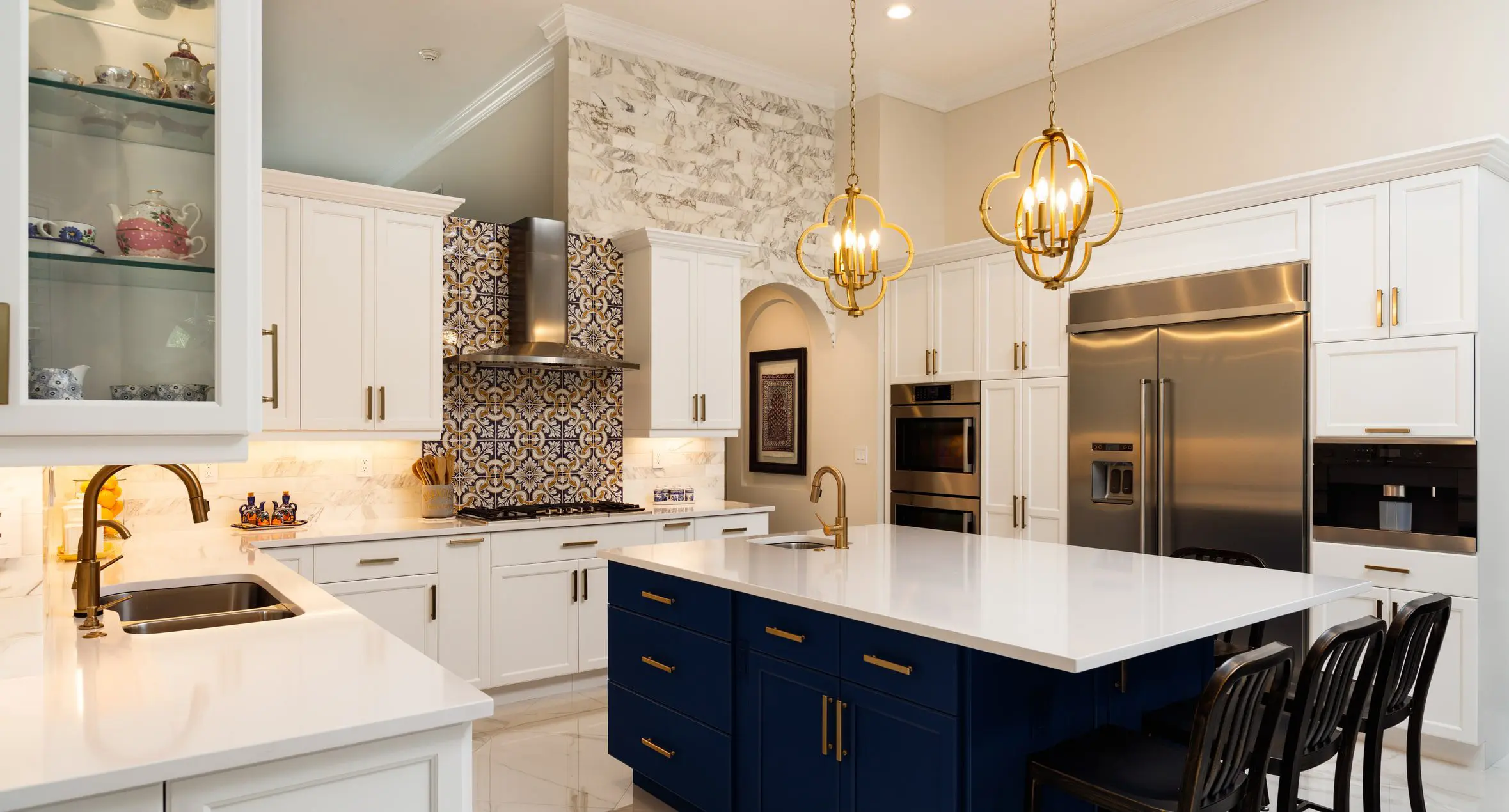 A kitchen with white cabinets and blue island.