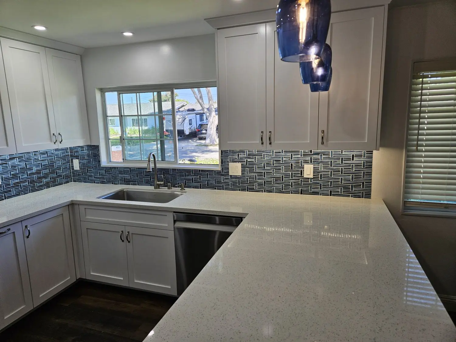 A kitchen with white cabinets and blue tile backsplash.