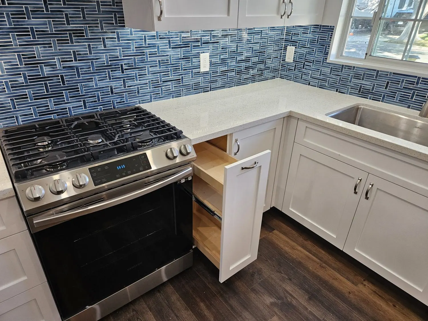 A kitchen with white cabinets and blue brick wall.