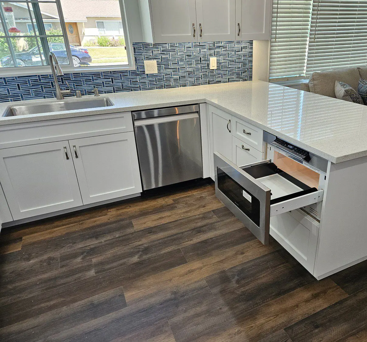 A kitchen with white cabinets and wood floors.