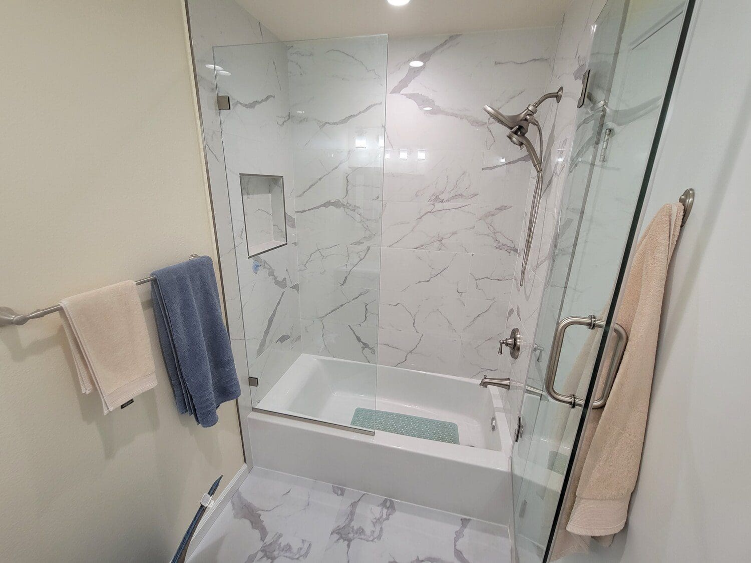 A bathroom with marble walls and floors, and a tub.