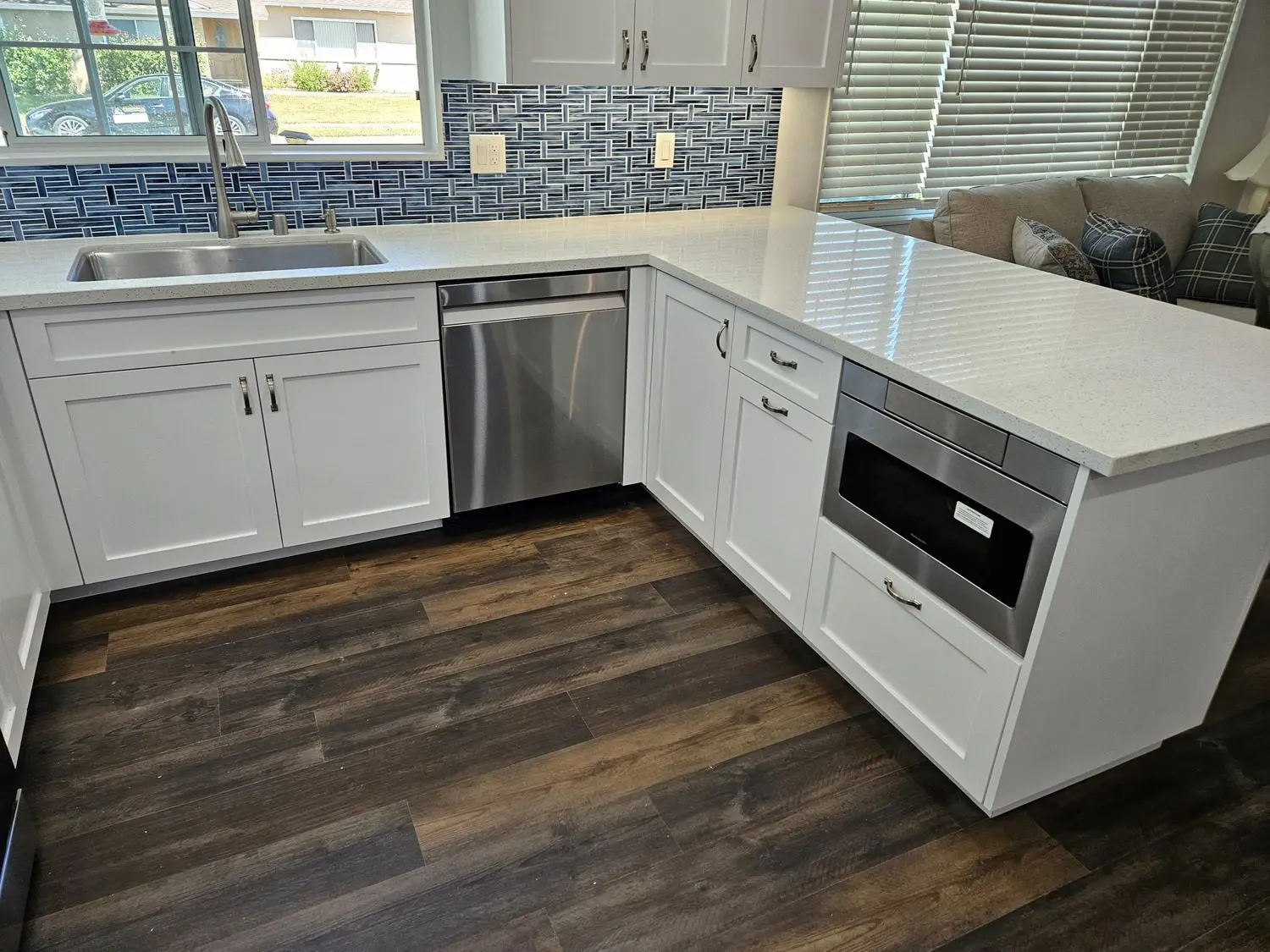 A kitchen with white cabinets and wood floors.