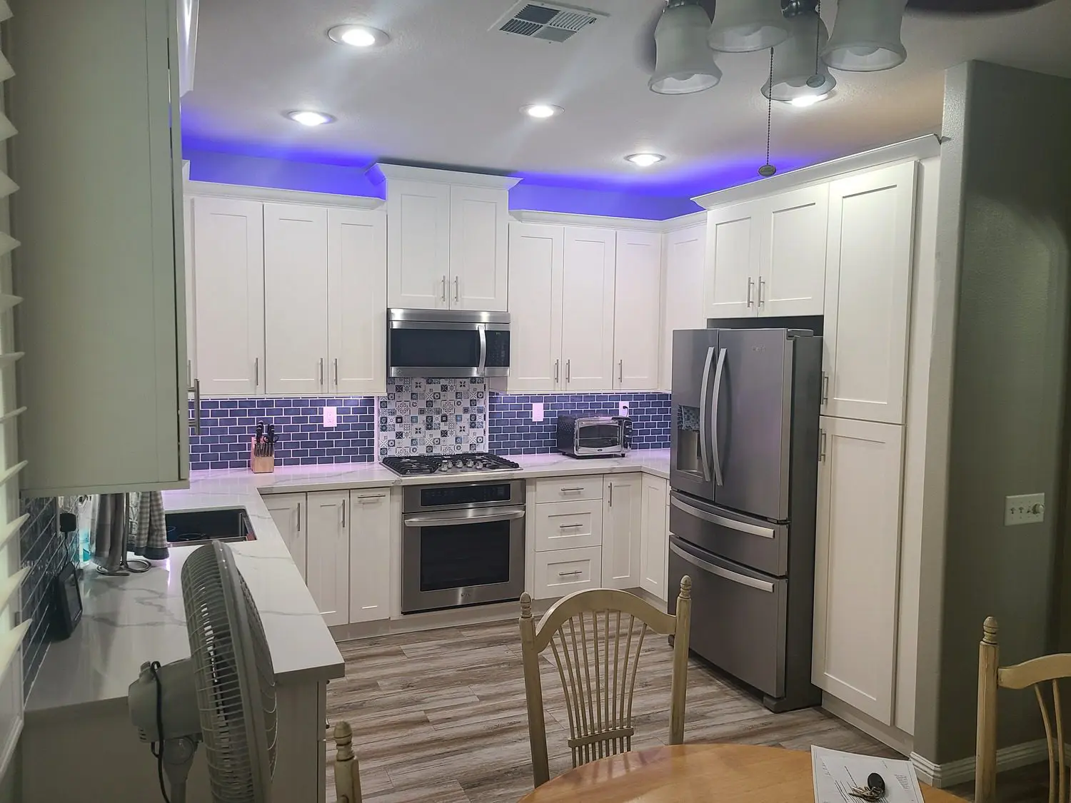 A kitchen with white cabinets and blue lights