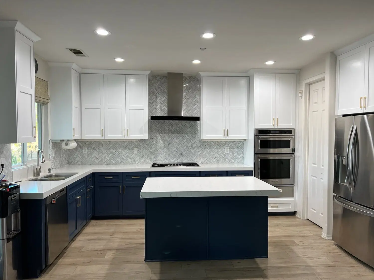 A kitchen with white cabinets and blue island.