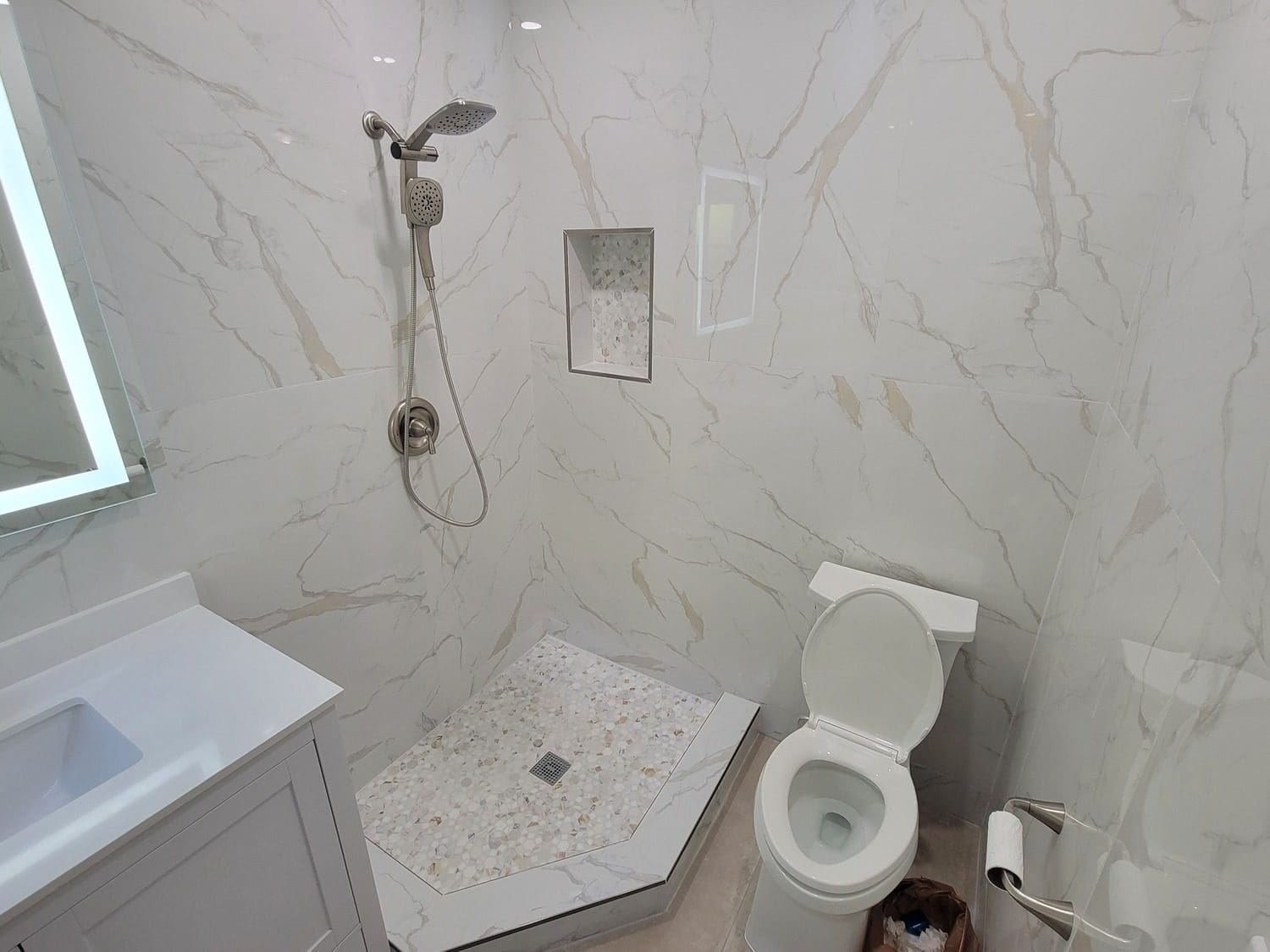 A bathroom with white marble walls and floors.