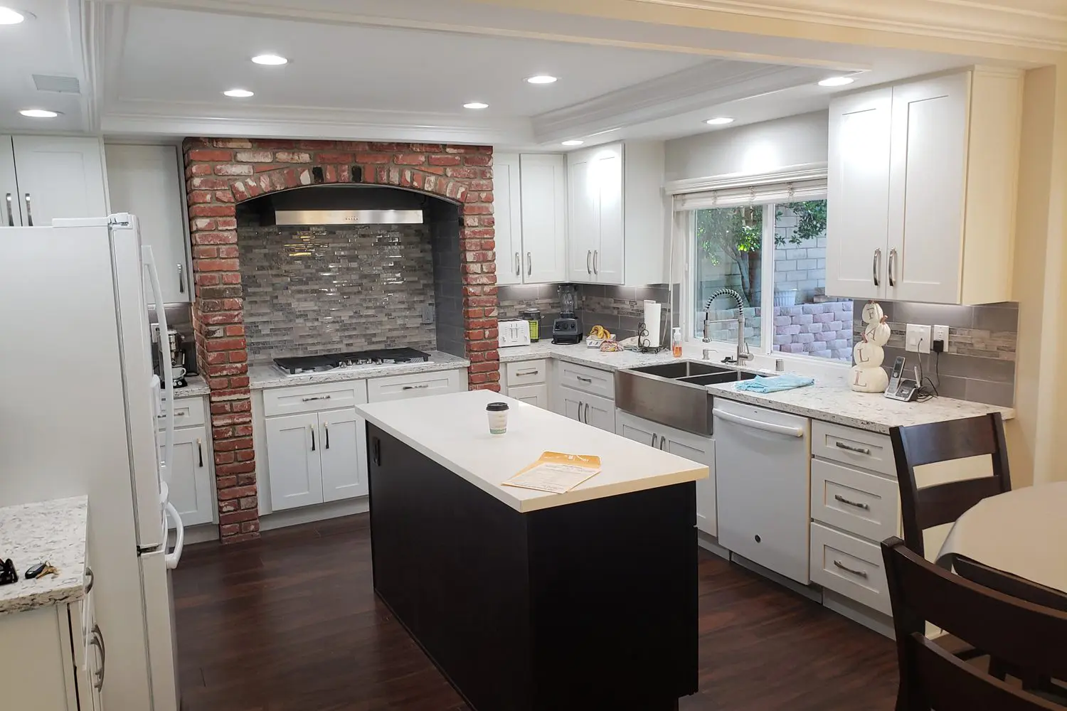 A kitchen with white cabinets and brick wall