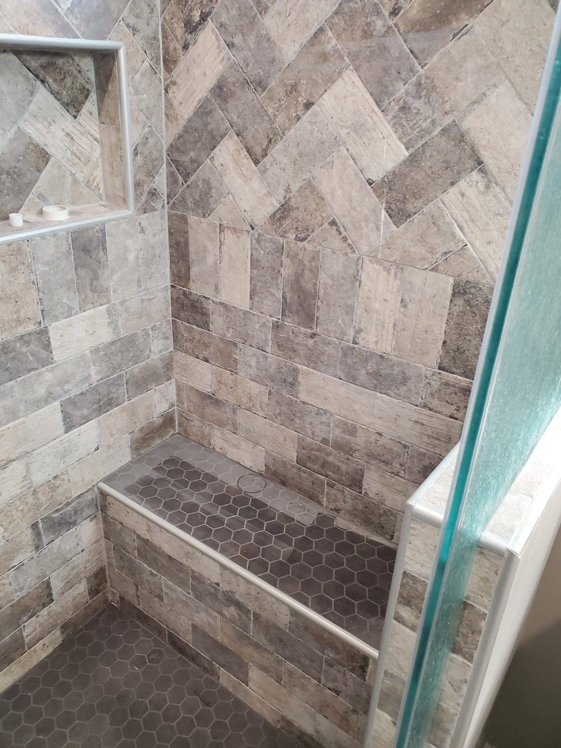 A tiled shower with a bench seat in the middle.