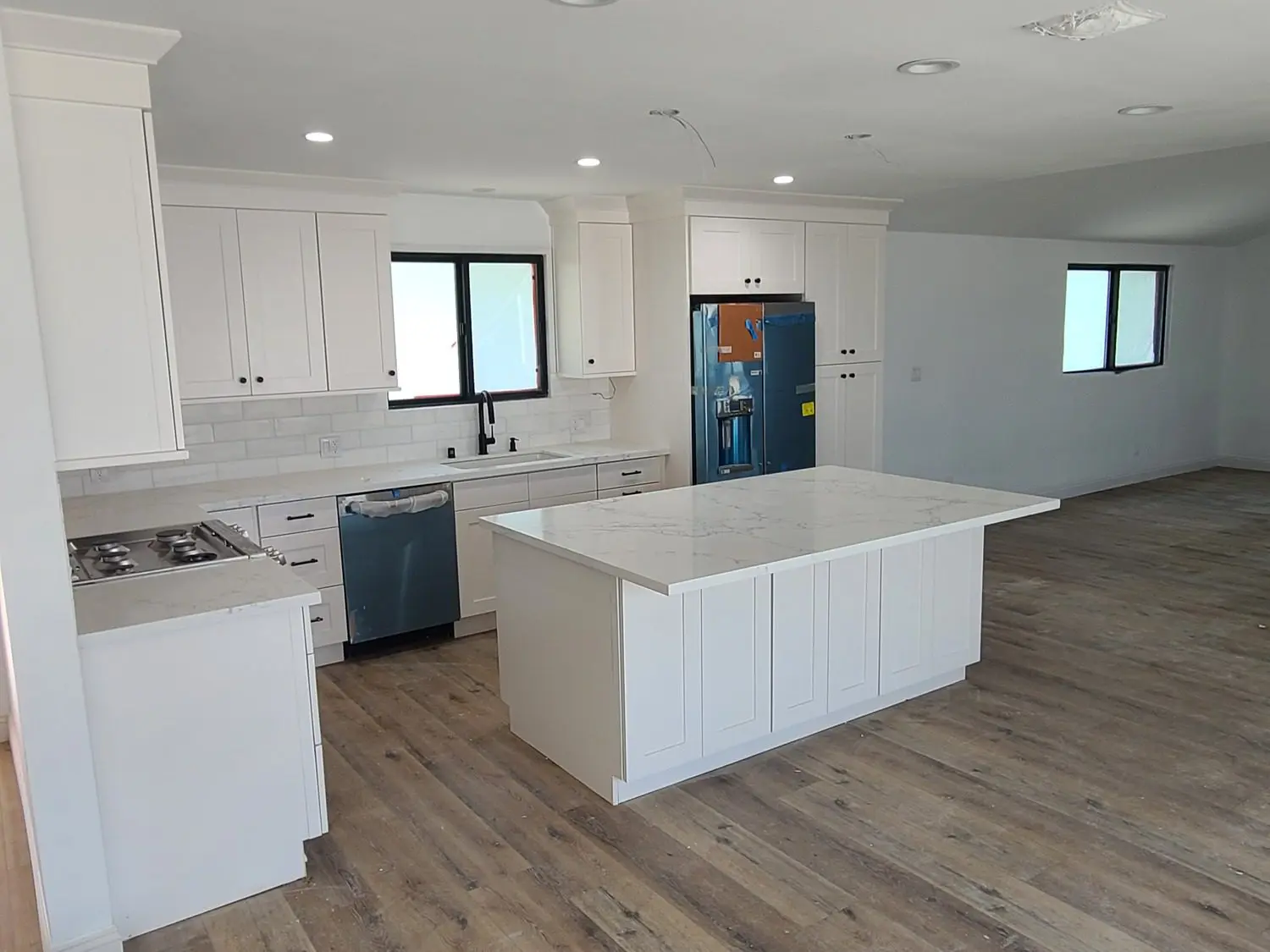 A kitchen with white cabinets and wood floors.