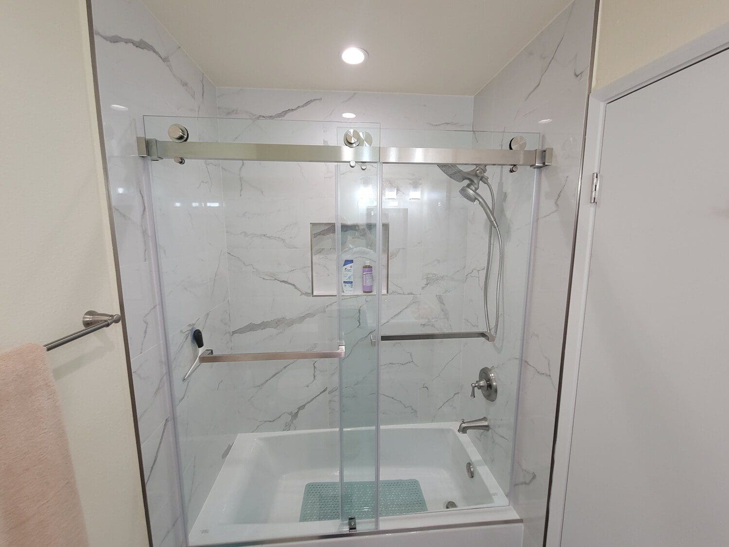 A bathroom with a glass shower door and white walls.