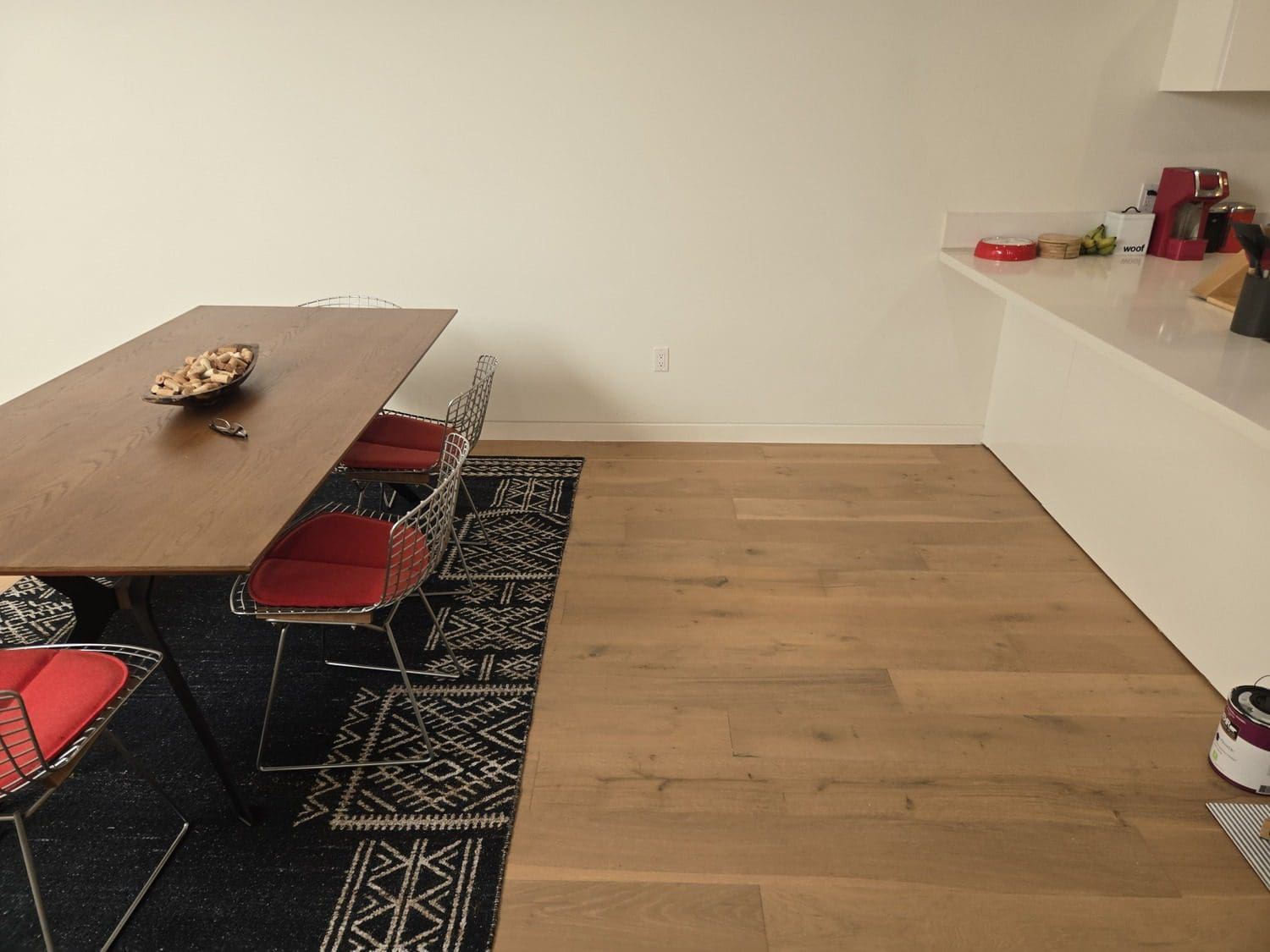 A room with a table and chairs, a rug and a wall.