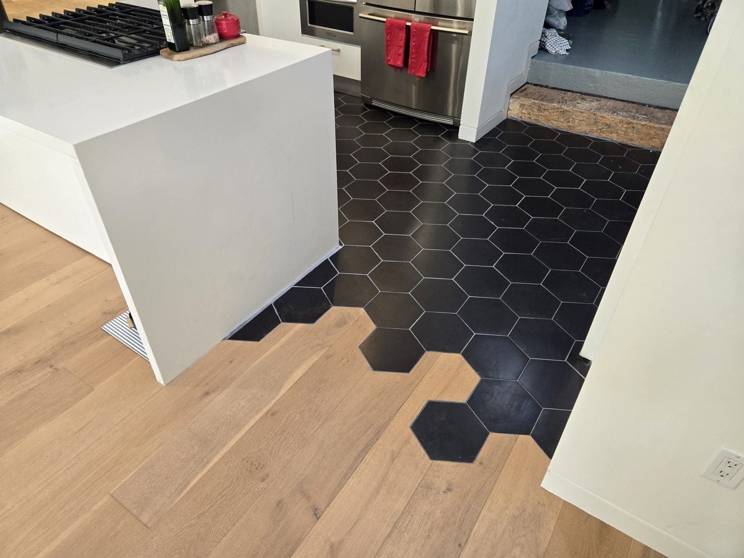 A kitchen with black hexagonal tiles on the floor