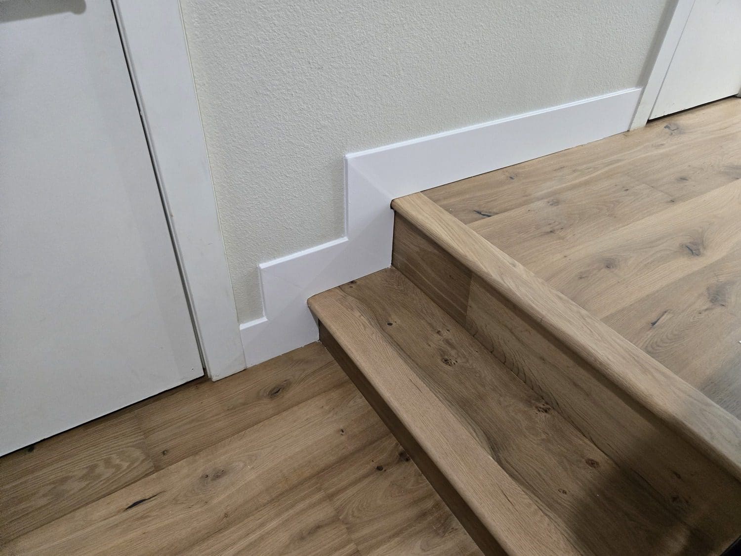 A wooden staircase with white trim and wood floors.