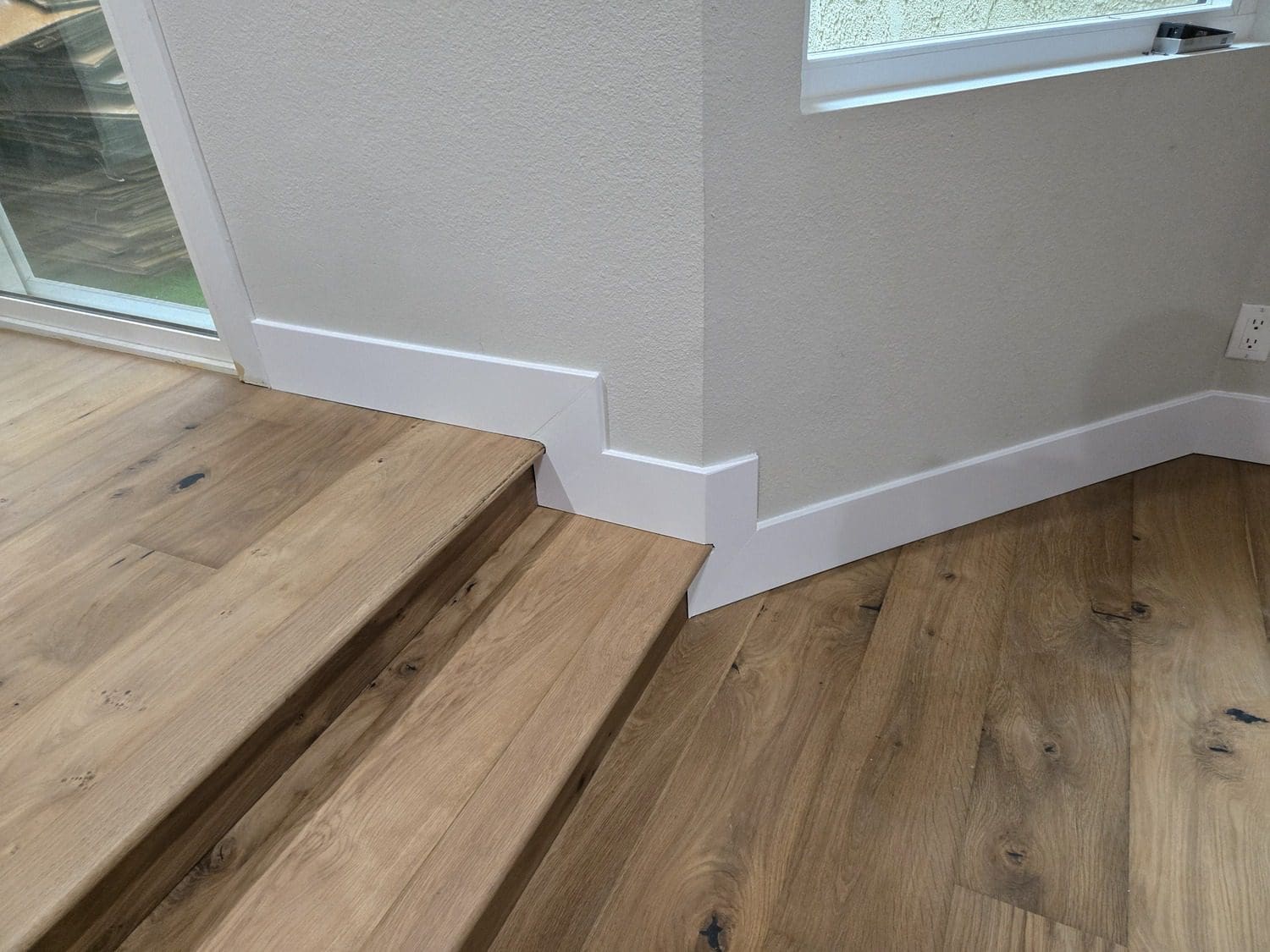 A wooden floor with white trim and wood stairs.