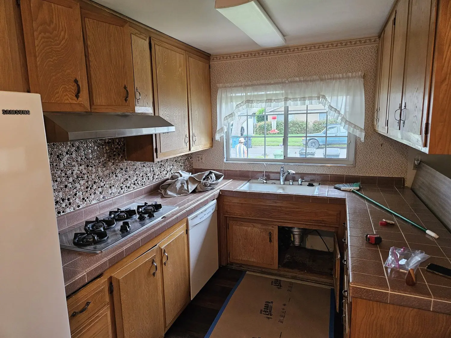 A kitchen with wooden cabinets and white counters.