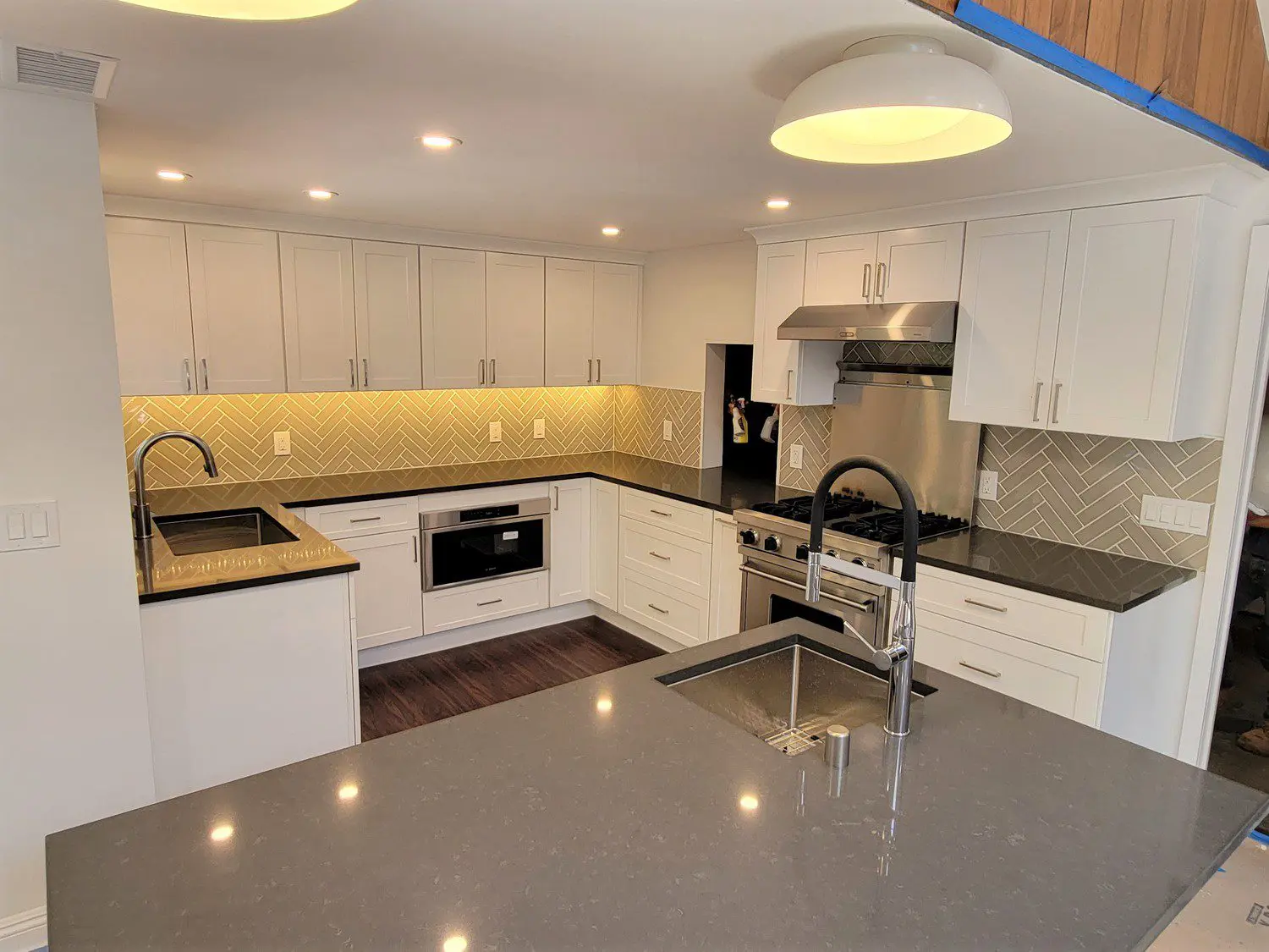 A kitchen with white cabinets and black counter tops.