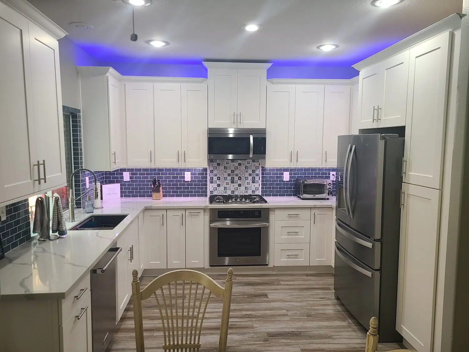 A kitchen with white cabinets and blue lights