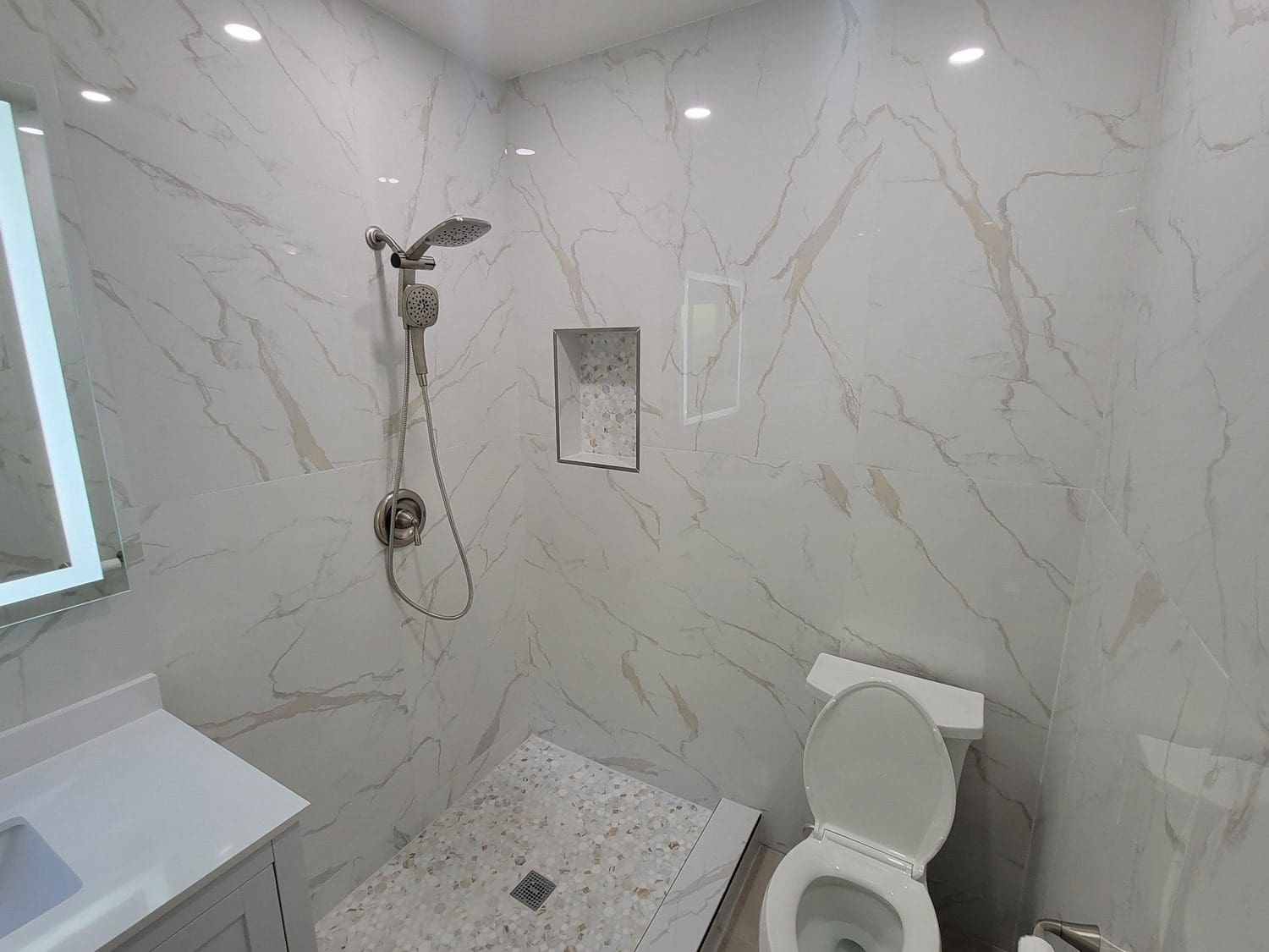 A bathroom with white marble walls and floors.