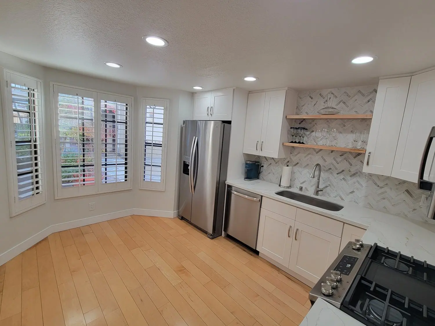 A kitchen with white cabinets and wooden floors.