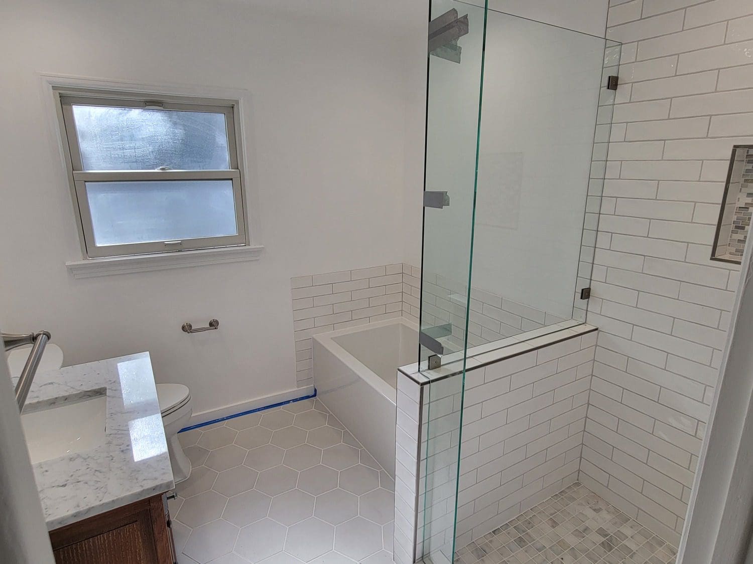 A bathroom with a tub, toilet and shower.