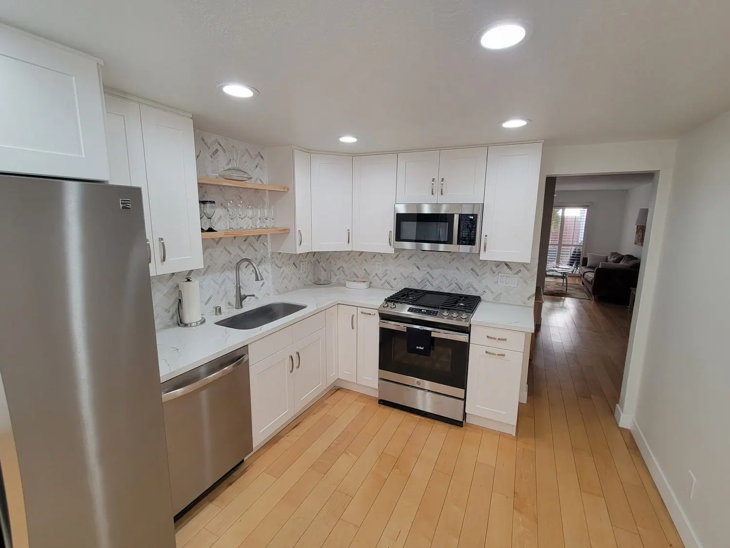 A kitchen with white cabinets and wood floors.