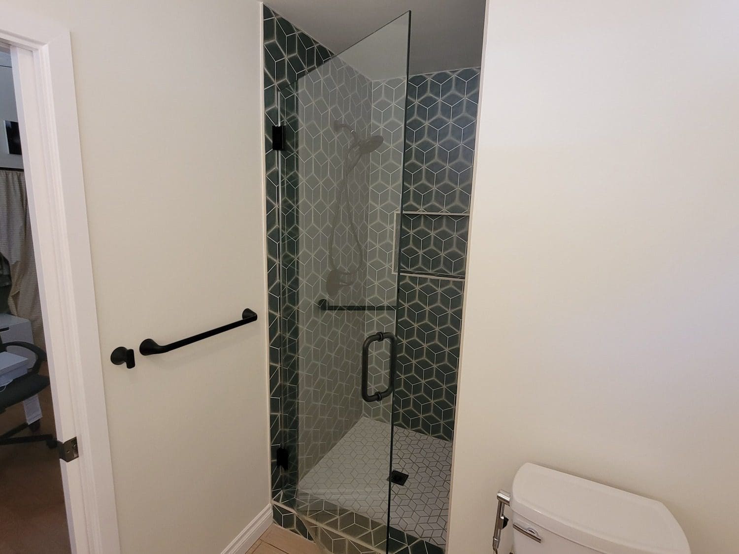 A bathroom with a glass shower door and tiled walls.