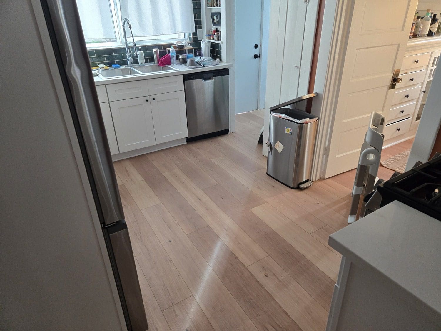 A kitchen with hard wood floors and white cabinets.