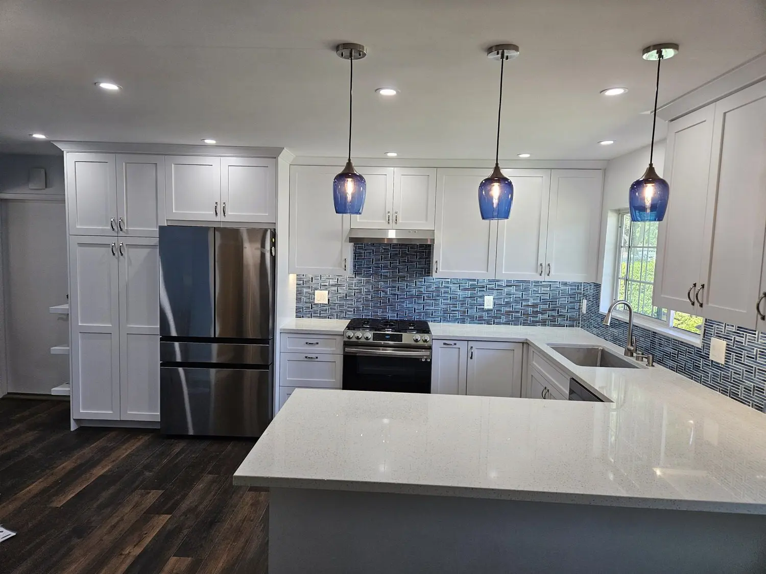 A kitchen with white cabinets and blue glass lights.