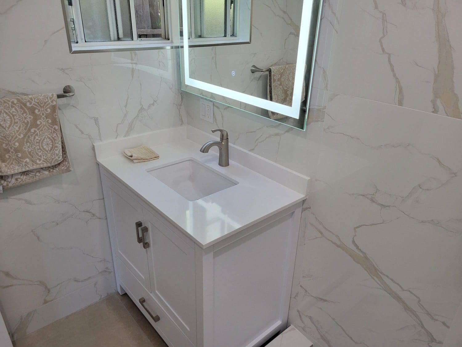 A bathroom with white walls and marble floors.