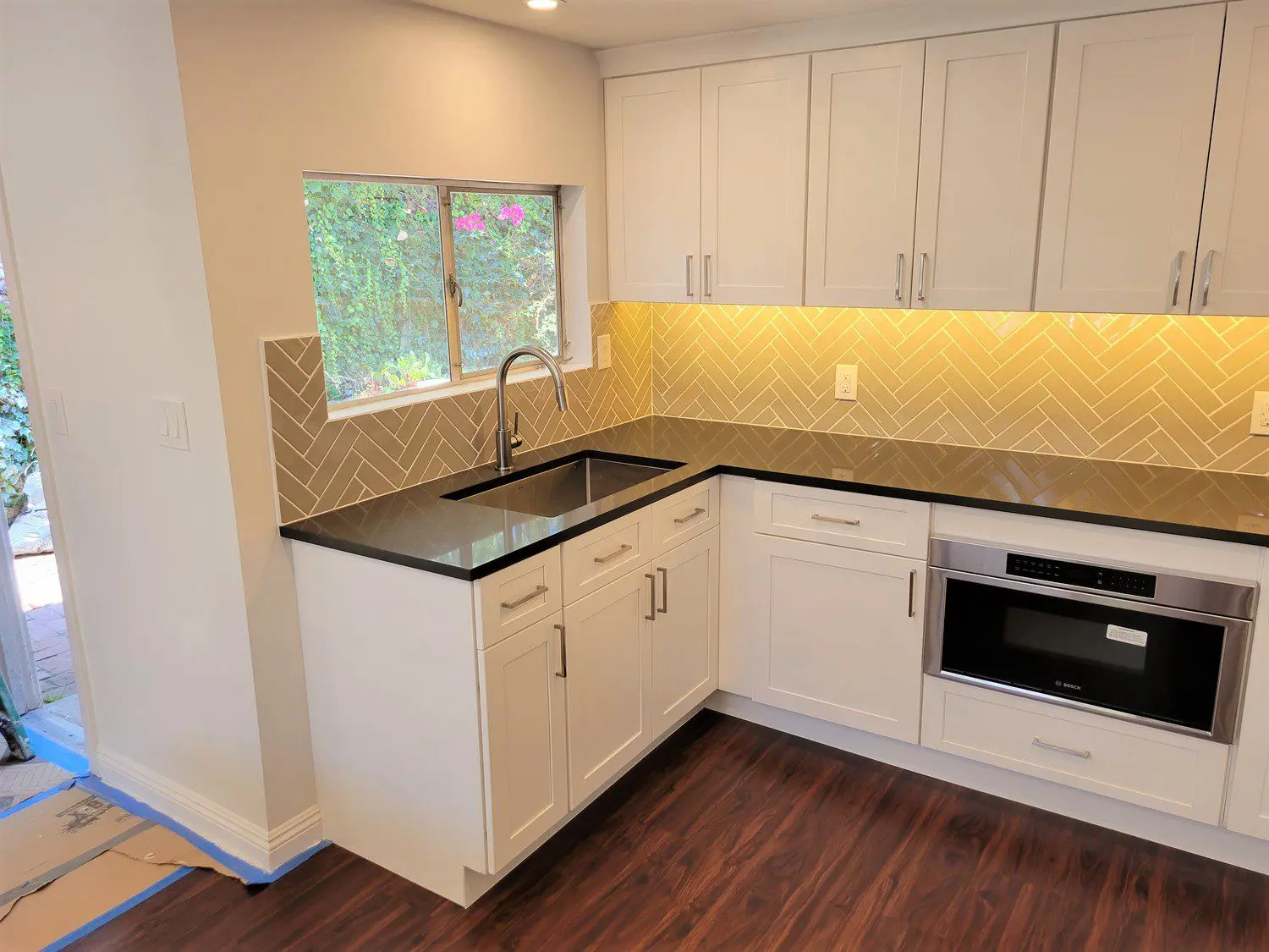 A kitchen with white cabinets and black counter tops.