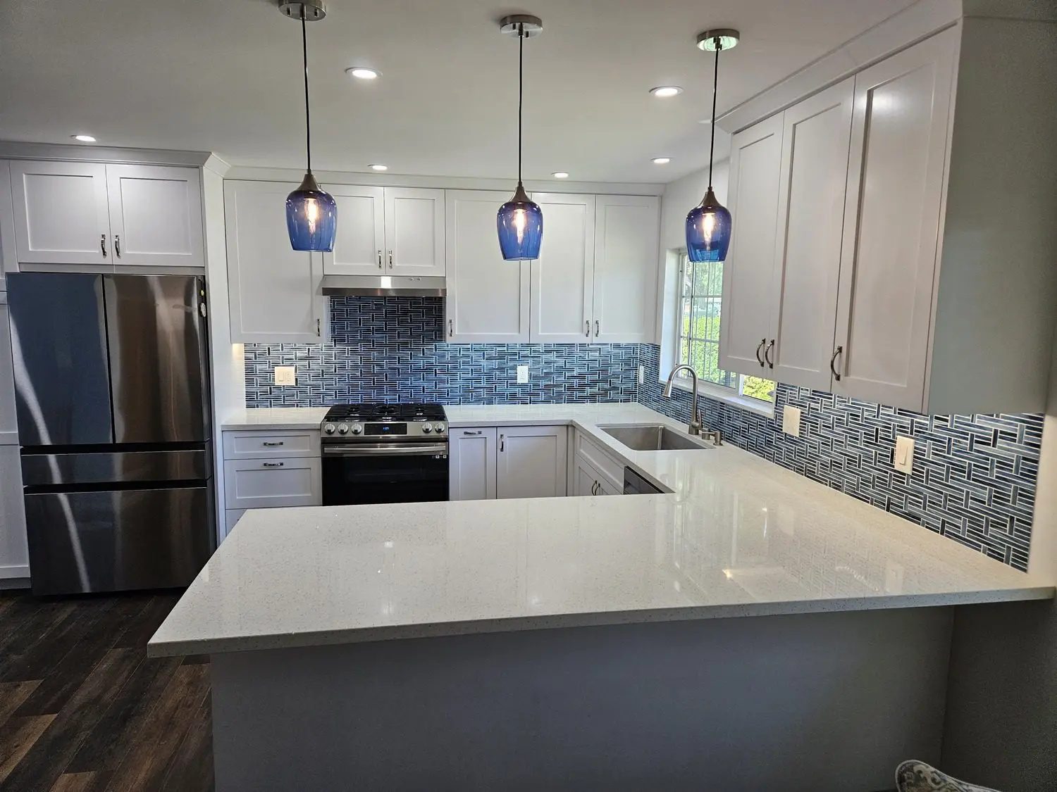 A kitchen with white cabinets and blue glass lights.