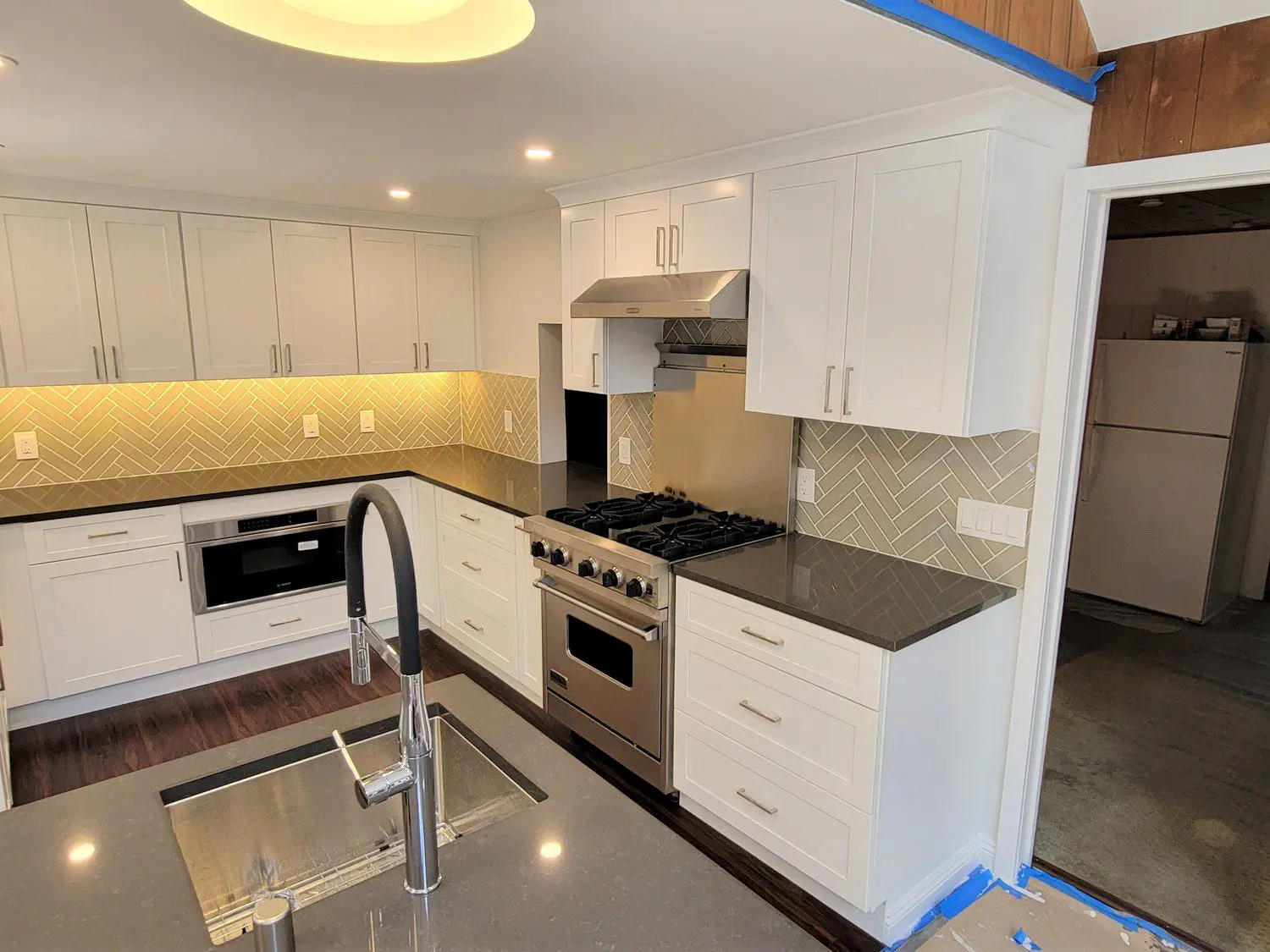 A kitchen with white cabinets and black counter tops.