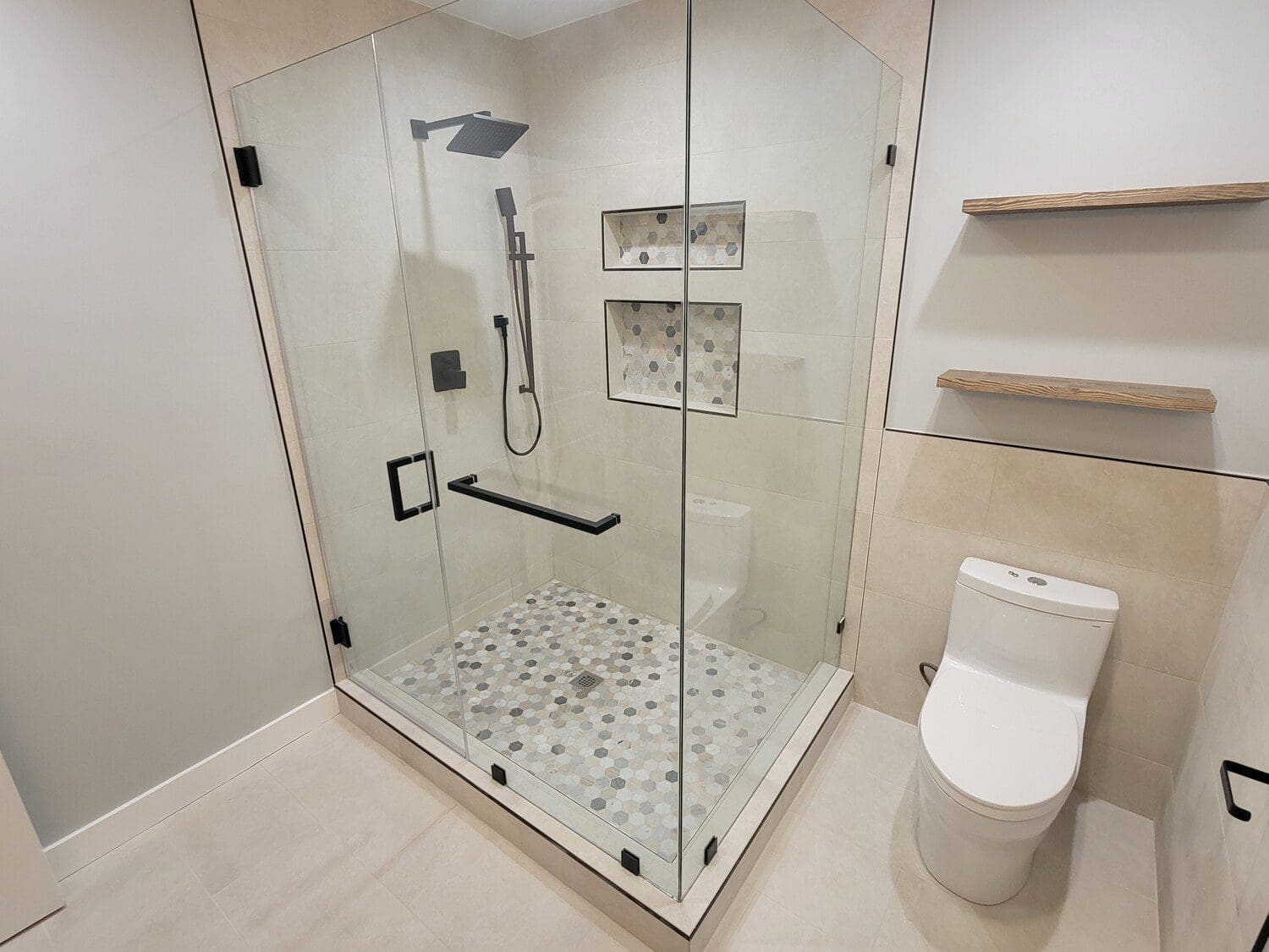 A bathroom with a glass shower door and tiled floor.