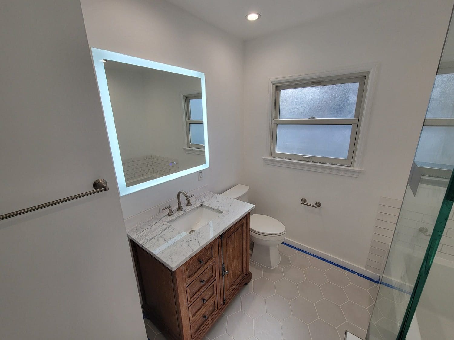 A bathroom with a sink, toilet and mirror.