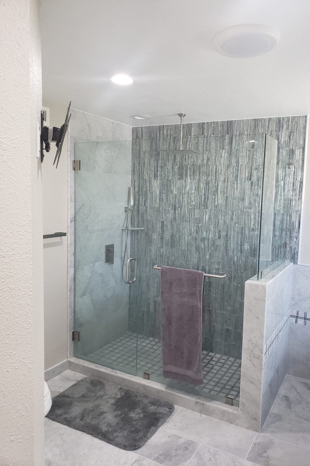 A bathroom with a glass shower door and tiled walls.