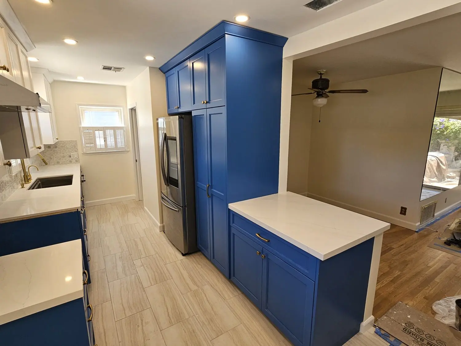 A kitchen with blue cabinets and white counter tops.