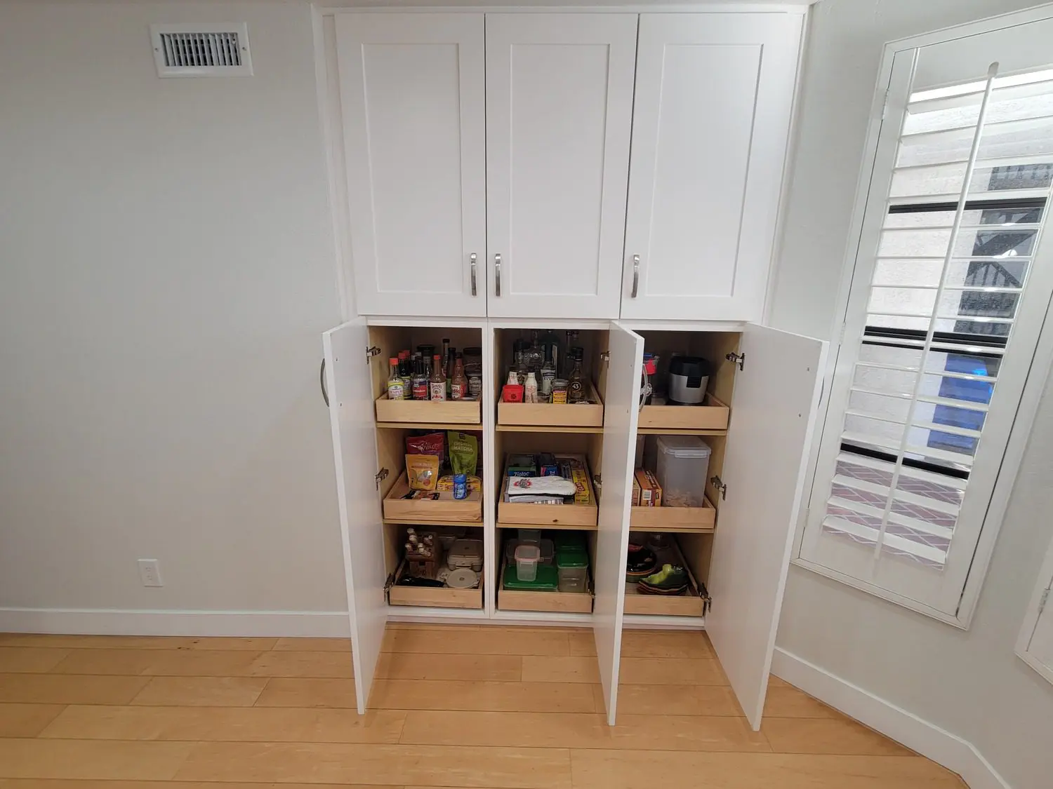 A white cabinet with many shelves and drawers.