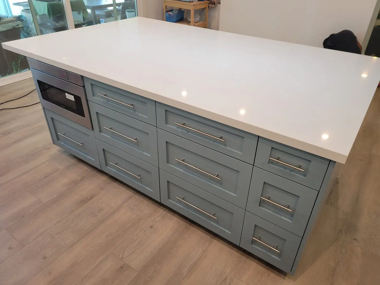 A kitchen island with drawers and a microwave on top.