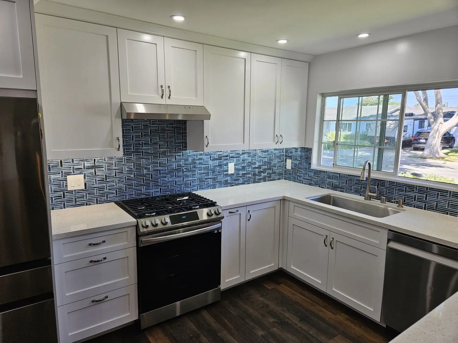 A kitchen with white cabinets and blue tile backsplash.