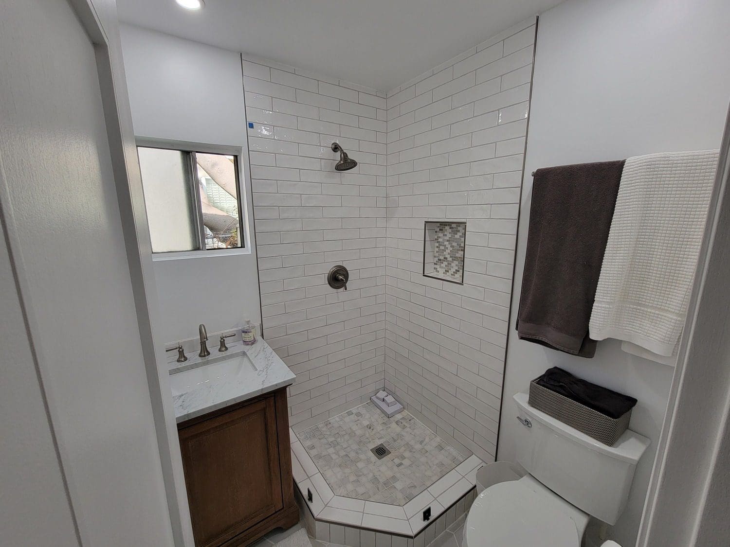 A bathroom with a toilet, sink and shower.